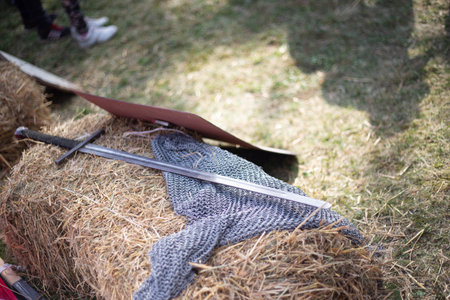 Medieval sword and chainmail armor lie on a hay bale, possibly at a historical reenactment or festivalの写真素材