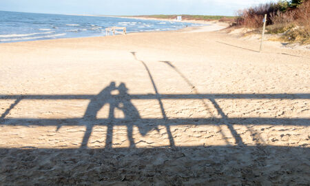 Shadow of a hugging couple on a beachの写真素材