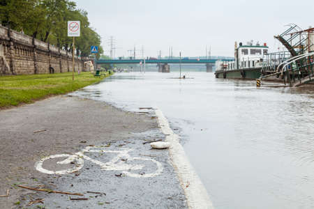 Flood. Sidewalk covered with water from the river in Krakow, Poland. Boats used as restaurants are closed.のeditorial素材