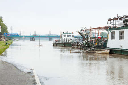 Flood. Sidewalk covered with water from the river in Krakow, Poland. Boats used as restaurants are closed.のeditorial素材