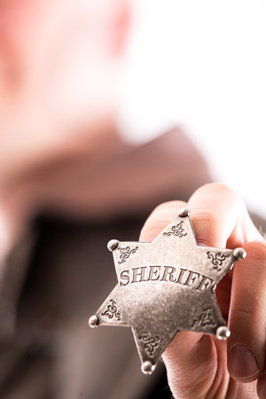 Man holds sheriff badge isolated on white backgroundの写真素材