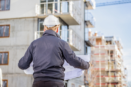 Construction manager with blueprints standing in front of construction site.の写真素材