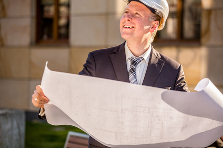 Construction manager with blueprints standing outdoor .の写真素材