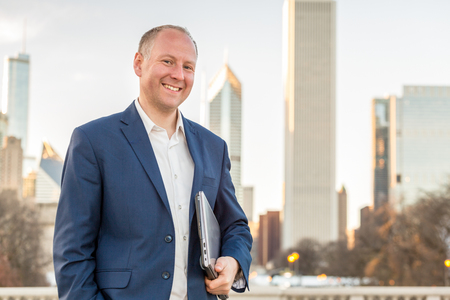 Businessman with laptop in front of skyscrapersの写真素材