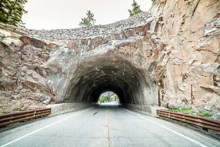 Asphalt road leading through rocky tunnel