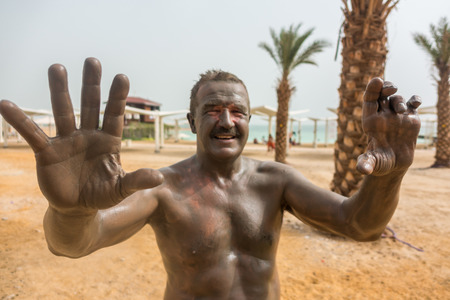 Man enjoying mud from Dead Sea, Israel, Middle Eastの写真素材