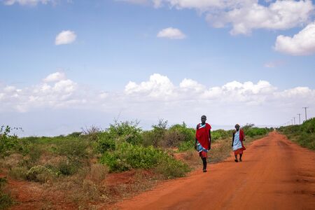 Taveta, Kenya - December 27, 2017: Two maasai men in traditional clothes walking on red african groundのeditorial素材