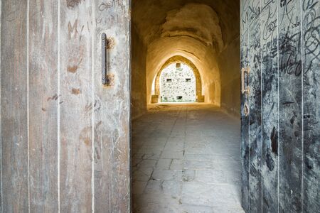 Entrance to abandoned fortress through big wooden gate, Italy