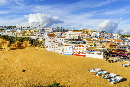 Sandy beach with colorful boats between cliffs and in front of charming white architecture in Carvoeiro, Algarve, Portugalのeditorial素材