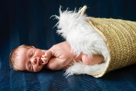 A newborn baby boy sleeping in the basketの写真素材