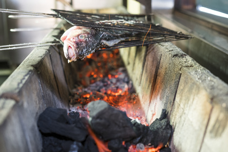 Big golden fish grilled on charcoal on the barbeque in the restaurant