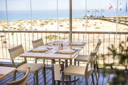 Table with plates, glasses and silverware ready for lunch in a sea view restaurantの写真素材