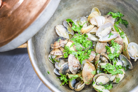 Clams with garlic and coriander in a copper, bronze pot with lidの写真素材