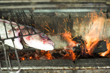 Big golden fish grilled on charcoal on the barbeque in the restaurant
