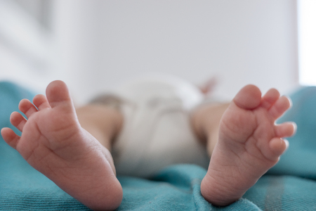 Cute feet with splayed toes of newborn baby on blue blanketの写真素材