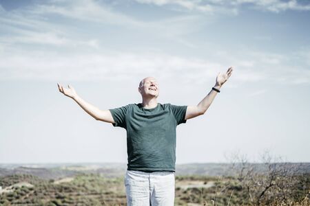 Man in the wilderness enjoying sun streching his arms up, Portugal