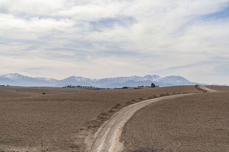 Dirt road through Agafay desert leading to Atlas Mountains, Moroccoの写真素材