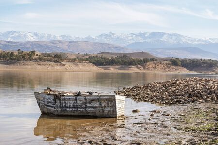 Wooden boat on the shore of Takerkoust lake with Atlas mountains in the background, Marrakech, Moroccoの写真素材
