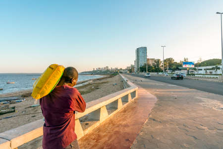 Maputo, Mozambique - May 13,2019: Man carrying heavy bag on his arm on  Costa do Solのeditorial素材