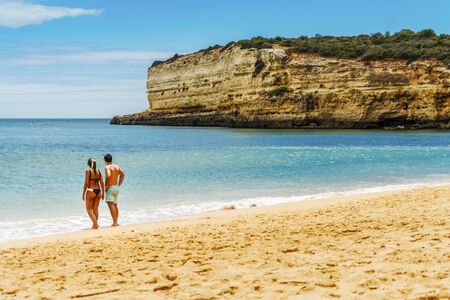 Young couple enjoying beautiful, sandy beach with cliffs in Algarve, Portugalの写真素材