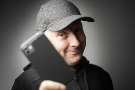 Content man in black clothes showing smartphone to the camera