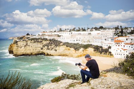 A man taking photo of beautiful holiday destination - white architecture, beach and Atlantic ocean, Carvoeiro, Portugalの写真素材