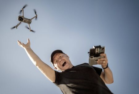 Desperate man tries to catch drone that flies awayの写真素材