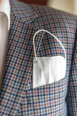 Elegant man with protective mask as handkerchief in chest pocket of his suit