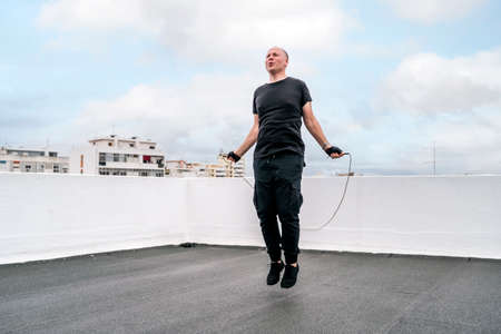 A man exercising on the rooftop using a jumping rope during the lockdown, Portugalの写真素材