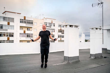 A man exercising on the rooftop using a jumping rope during the lockdown, Portugalの写真素材