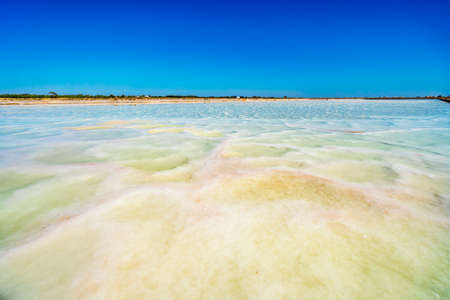 Shallow pond with salty water used to extract salt from the ocean in salines in Faro, Algarve, Portugalの写真素材