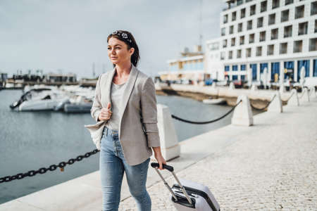Young woman with suitcase walking in urban settings, Faro, Portugalの写真素材