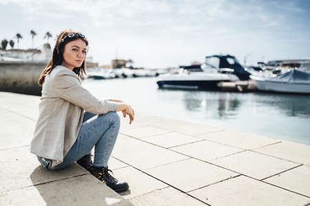 Young woman sitting by the marina in Faro, Algarve, Portugalの写真素材
