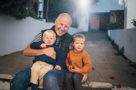 Father with his two sons hugging each other outdoor during fall