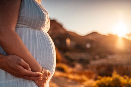 Pregnant woman with her partner holding her belly in the nature