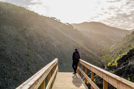 A man contemplating the beauty of the mountains from a boardwalk in Alferce, Algarve, Portugal