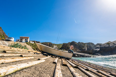 Coastal view of Azenha do Mar in Portugal, featuring turquoise waters, rocky cliffs, and a small fishing harbor under a clear blue sky.の写真素材