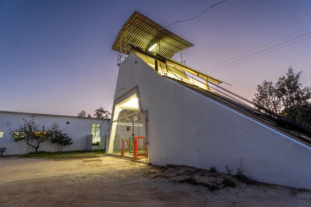Exterior of an industrial mine site with simple buildings, ventilation structures, and service...
