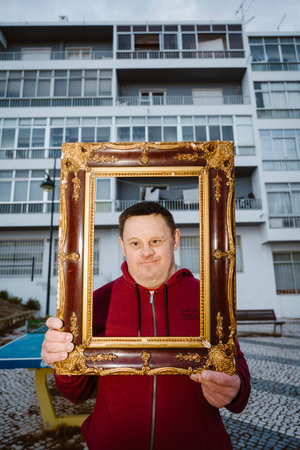 Faro, Portugal -  March 10, 2026: Portrait of adult man with Down syndrome in front of a residential...