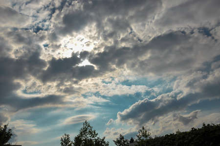 Sky with dramatic clouds and treetops in the foreground