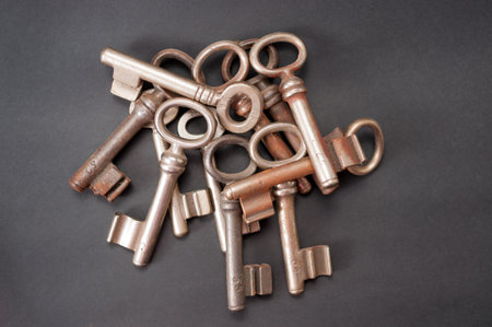 Piled up old mustache keys. They are rusty in different ways and lie on a black backgroundの写真素材