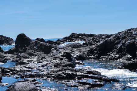 Volcanic coastal landscape, with a churned sea, which glistens in the midday sunの写真素材