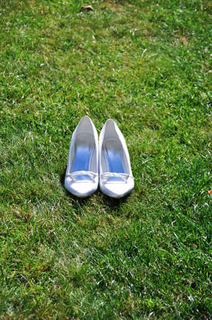 Wedding shoes with a small bow are arranged on a lawnの写真素材