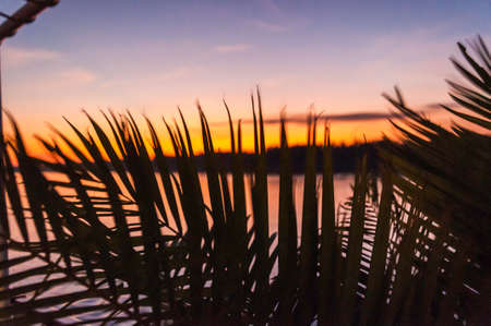 Evening mood on the Mekong. View from a river ship with railing on the shore with the setting sun
