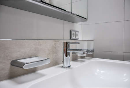 Detail of a vanity unit, with unusual tiles. Furthermore, a modern soap holder and a section of a mirror cabinet can be seenの写真素材