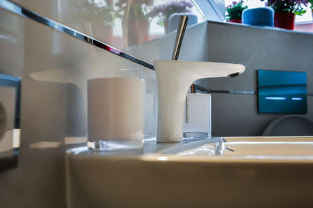 Modern, unusual and stylish basin mixer, white faucet. The bathroom is modern with beautiful wall tilesの写真素材