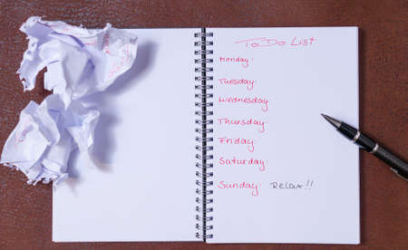 To-do list for a week. Open notebook with black cover on brown background. . Large text field