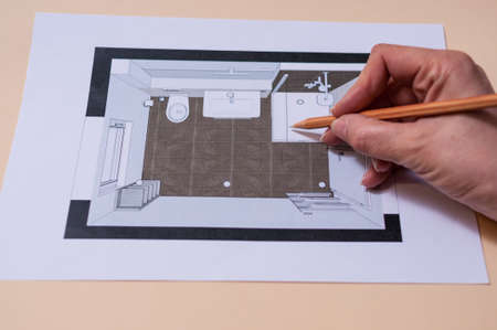 Planning a tubular bathroom with shower. A hand holds a pencil and draws in the planning