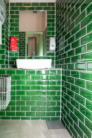 Glance into an extraordinary guest toilet. with attached washbasin. The small dark green tiles are...