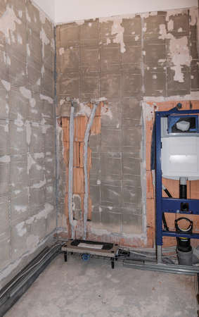Glance into a bathroom where the installation has already started. The drinking water pipes and the toilet element are already doneの写真素材